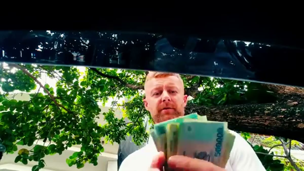 Marcin mit einem Fächer aus 500.000-Dong-Scheinen unter einem Baum in Da Nang