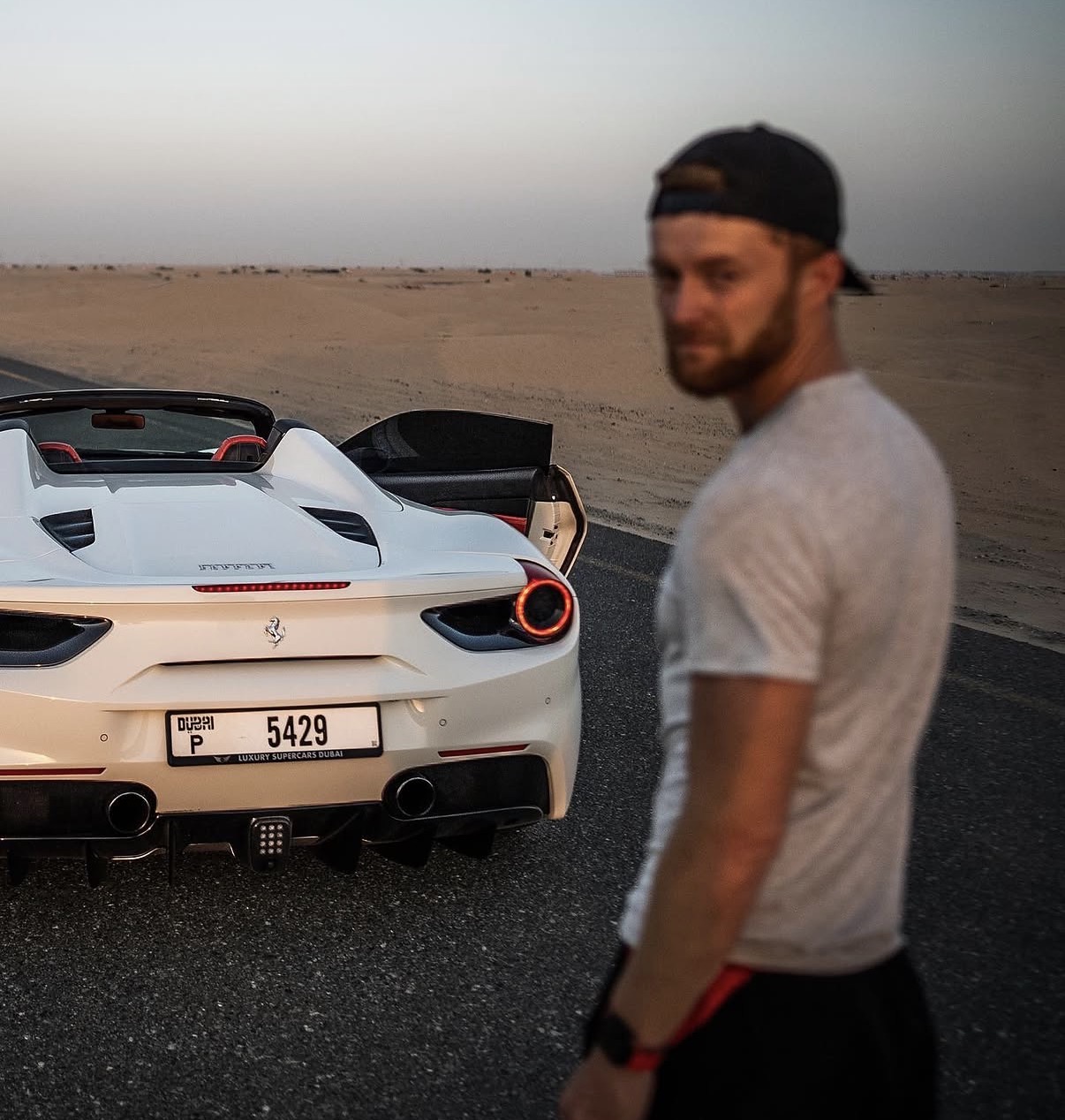 Marcin neben einem weißen Ferrari in der Wüste bei Dubai