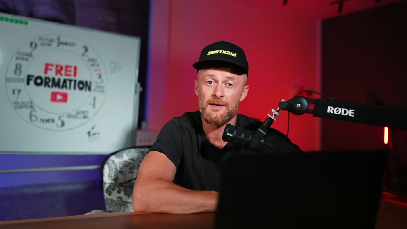 Marcin am Schreibtisch vor dem Freiformation-Whiteboard, Blick in die Kamera