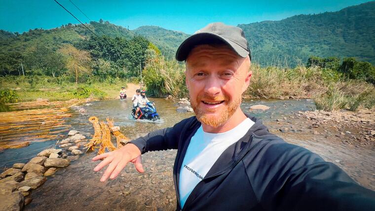 Selfie am Fluss, hinten fährt einer durchs Wasser
